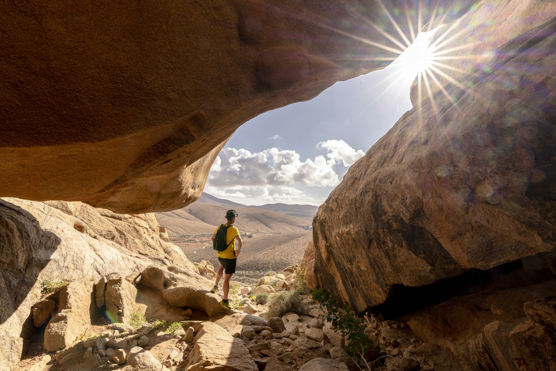 Person watching the sun standing inside a sandstone rock cave, Barranco de las Penitas, Fuerteventura
