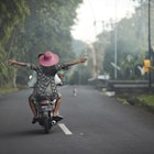 Woman with arms outstretched sitting on scooter rode by female friend during vacation
1475727166