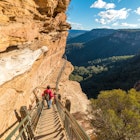 Mountain landscape with a woman hiking, going downstairs mountain track. Wentworth Falls, Blue Mountains National Park, Australia