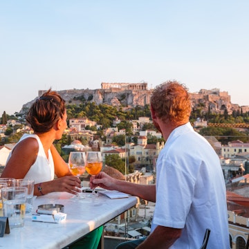 Couple drinking and enjoying the view of the Acropolis at sunset. Athens, Greece