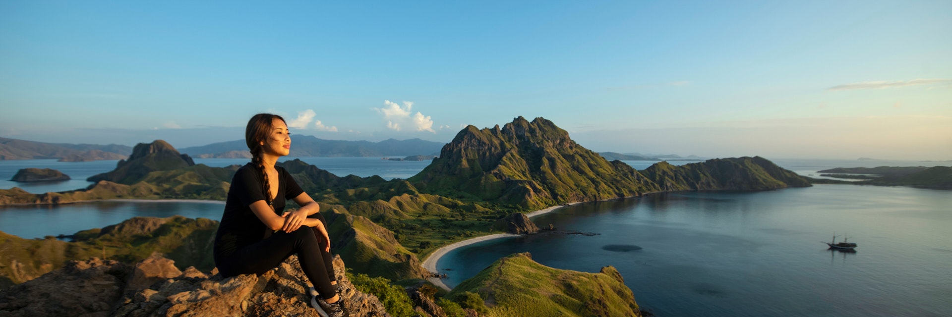 Scenic view with resting female pansian hiker on Padar island Komodo National Park, Indonesia. The mountainous seascape in Indonesia is famous for its incredible vistas.